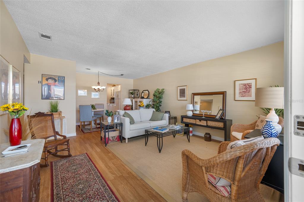 A living room with light walls, hardwood floors, wicker furniture, and a white sofa — 5217 81ST STREET N UNIT 16, ST PETERSBURG, FL