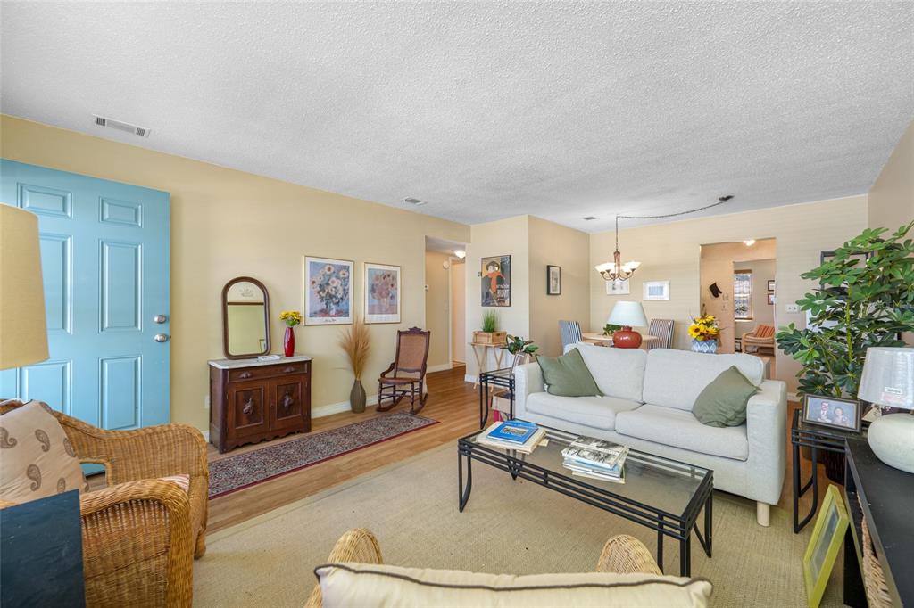 A living room features a light blue front door, a white sofa, and wood flooring — 5217 81ST STREET N UNIT 16, ST PETERSBURG, FL