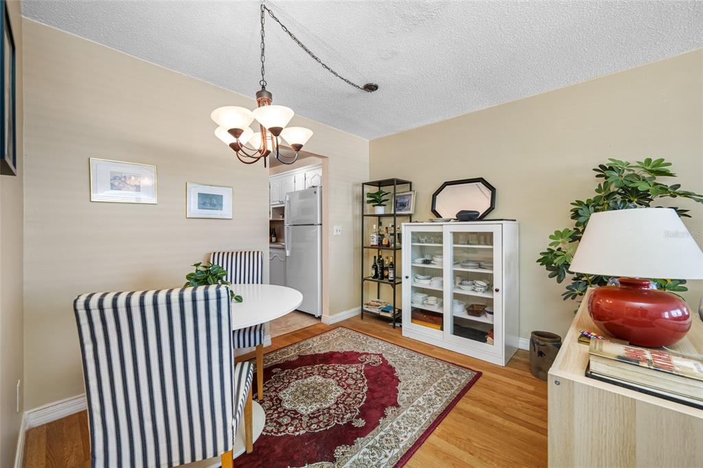 A dining room features a round table, striped chairs, a rug, and a white cabinet — 5217 81ST STREET N UNIT 16, ST PETERSBURG, FL