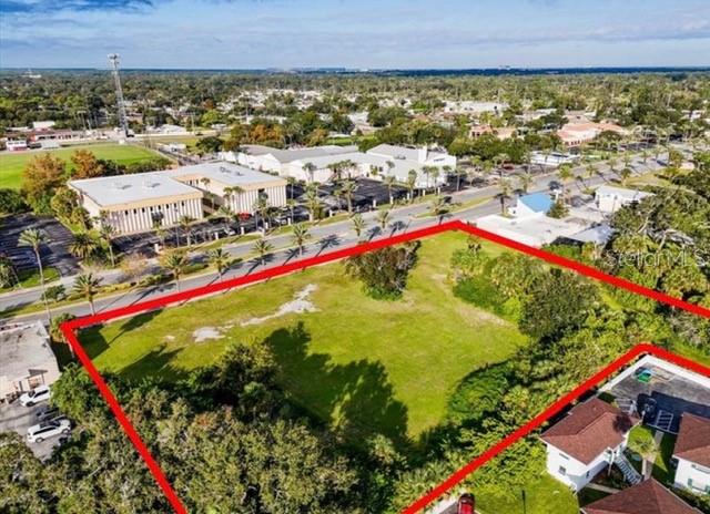 An aerial view shows a vacant, rectangular grassy lot outlined in red near a road — 1745 S RIDGEWOOD AVENUE, SOUTH DAYTONA, FL