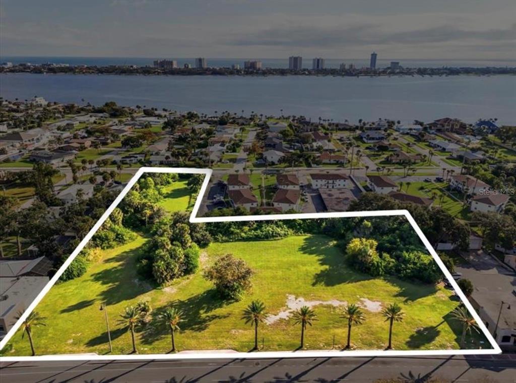 An aerial view shows a vacant, grassy lot outlined in white near a waterfront city — 1745 S RIDGEWOOD AVENUE, SOUTH DAYTONA, FL