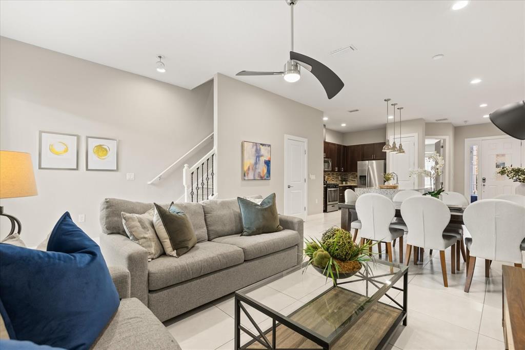 A living room with a grey sofa, glass coffee table, and open-concept kitchen area — 2637 SUNRISE SHORES DRIVE, KISSIMMEE, FL