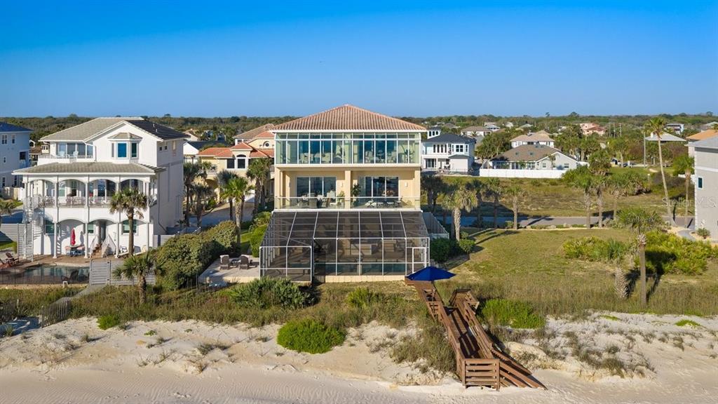 An aerial view of a three-story beachfront house with a screened-in pool and wooden walkway — 11 OCEAN DUNE CIRCLE, PALM COAST, FL