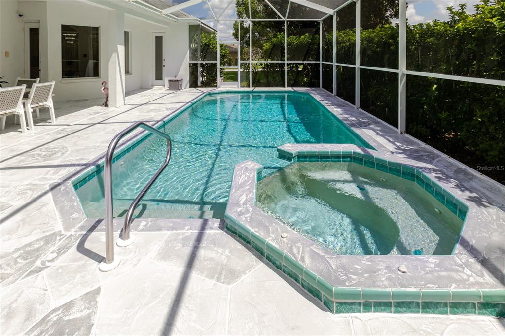 A rectangular swimming pool and attached spa are enclosed within a screened-in patio area — 13382 SAGEWATER COURT, SPRING HILL, FL