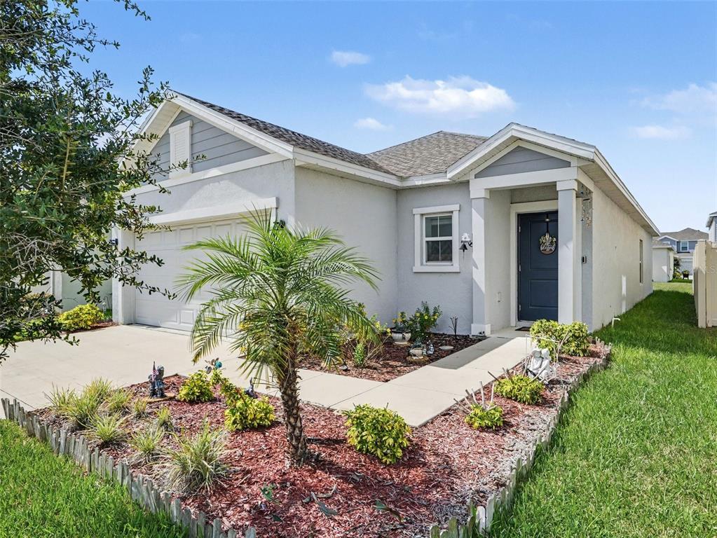 A single-story house with a gray exterior, a two-car garage, and a landscaped front yard — 625 TROTTERS DRIVE, EAGLE LAKE, FL