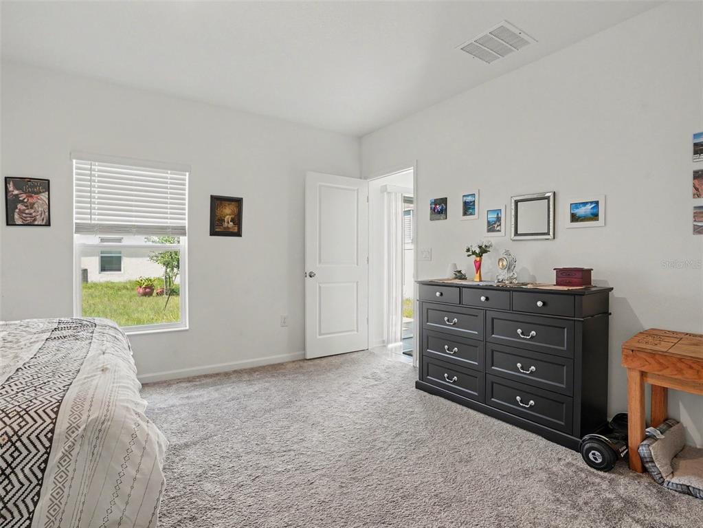 A bedroom features gray carpeting, white walls, a black dresser, and a window with blinds — 625 TROTTERS DRIVE, EAGLE LAKE, FL