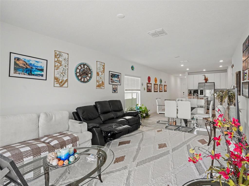 An open-concept living and dining area features white walls, tile flooring, and modern furniture — 625 TROTTERS DRIVE, EAGLE LAKE, FL