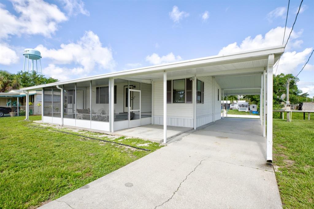 A single-story mobile home features a screened-in porch, a concrete driveway, and a covered carport — 3523 SE 35TH AVENUE, OKEECHOBEE, FL