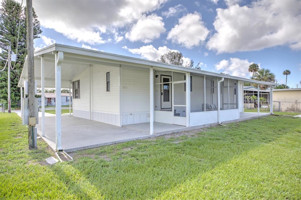 A white mobile home with a carport and a screened-in porch sits on a grassy lot — 3523 SE 35TH AVENUE, OKEECHOBEE, FL