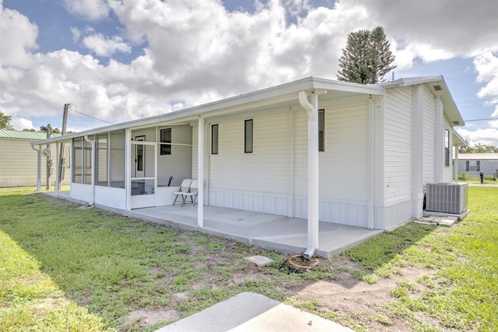A white mobile home features a screened-in porch and a concrete patio area — 3523 SE 35TH AVENUE, OKEECHOBEE, FL