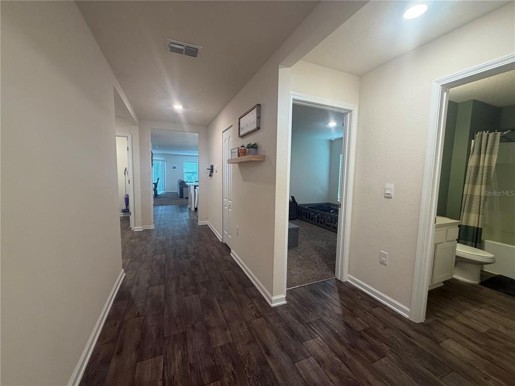 A hallway with wood-look flooring leads to a living area, a bedroom, and a bathroom — 703 GRAND RESERVE DRIVE, BUNNELL, FL