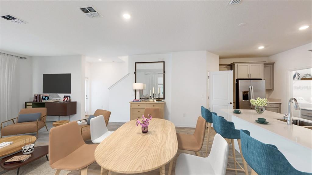 An open-concept living and dining area features a kitchen island with blue bar stools — 5654 KETTLEBELL ALLEY, CLERMONT, FL