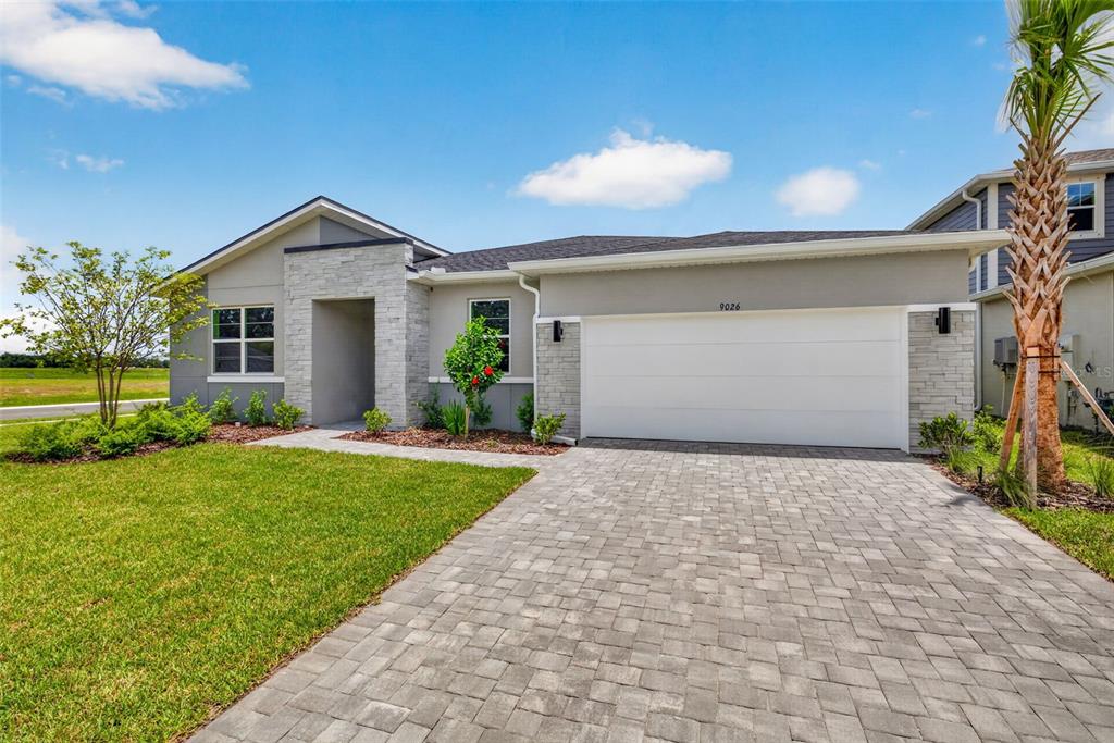 A single-story house with a stone-accented facade, a two-car garage, and a paved driveway — 9026 SUNDANCE TERRACE, PARRISH, FL