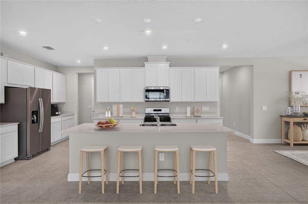 A modern kitchen features white cabinets, stainless steel appliances, and a large central island — 9026 SUNDANCE TERRACE, PARRISH, FL