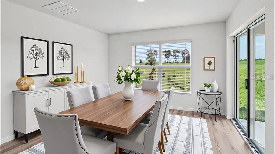 This dining room features a wooden table, gray upholstered chairs, and a sliding glass door — 8782 TRIUMPH CIRCLE, WILDWOOD, FL