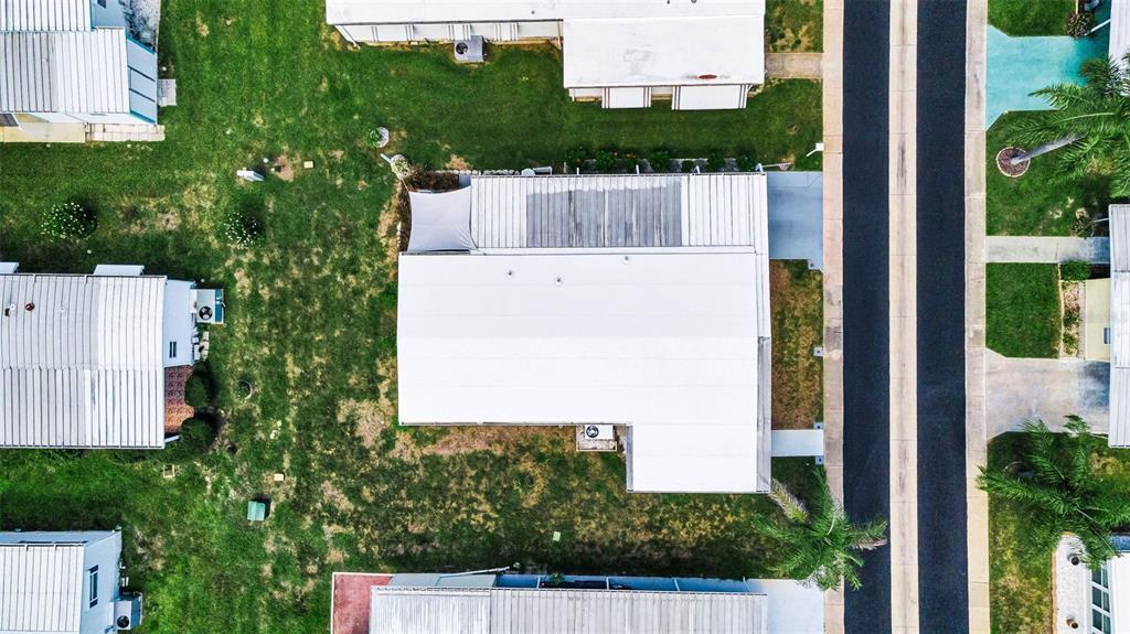 An aerial view shows a mobile home with a white roof surrounded by green grass — 143 MELODY LANE, TARPON SPRINGS, FL