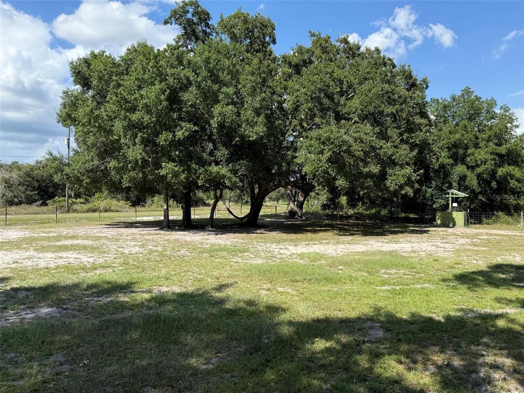 A large, grassy yard features several mature oak trees and a small green shed — 19084 NW 306TH STREET, OKEECHOBEE, FL