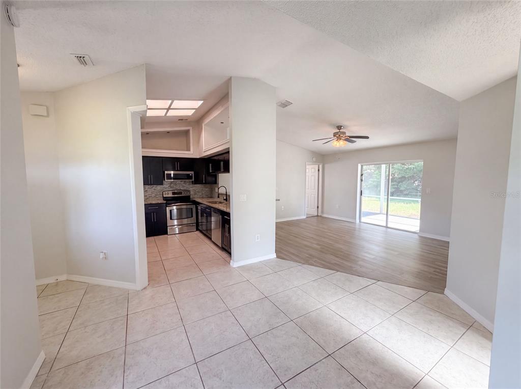 An open-concept interior features a tiled kitchen area transitioning into a living room with wood flooring — 11339 STACY STREET, SPRING HILL, FL