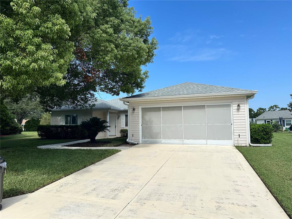 A single-story house with light siding, a concrete driveway, and a large shade tree — 13780 SW 115TH CIRCLE, DUNNELLON, FL