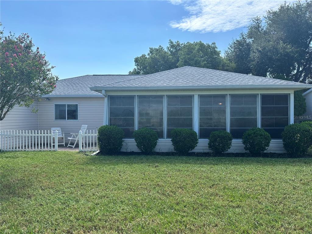 A backyard view of a house with a screened-in porch and a white picket fence — 13780 SW 115TH CIRCLE, DUNNELLON, FL