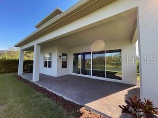 A covered patio with a paved floor overlooks a grassy yard and trees — 30791 LINDENTREE DRIVE, WESLEY CHAPEL, FL