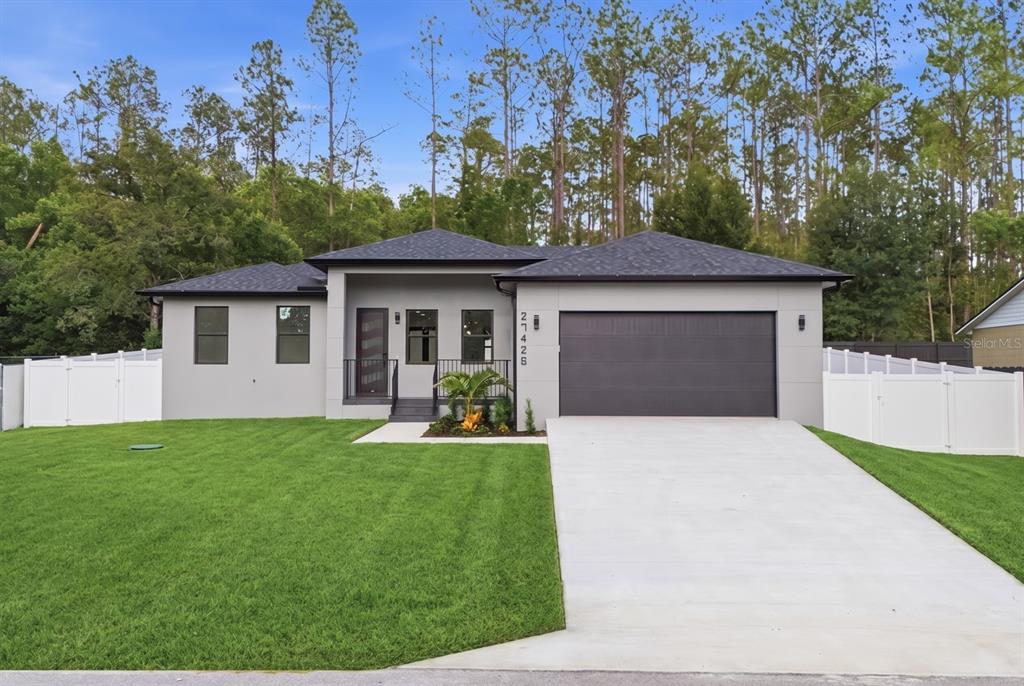 A modern single-story house with a gray exterior, dark roof, and a two-car garage — 27426 AZEN LOOP, BROOKSVILLE, FL