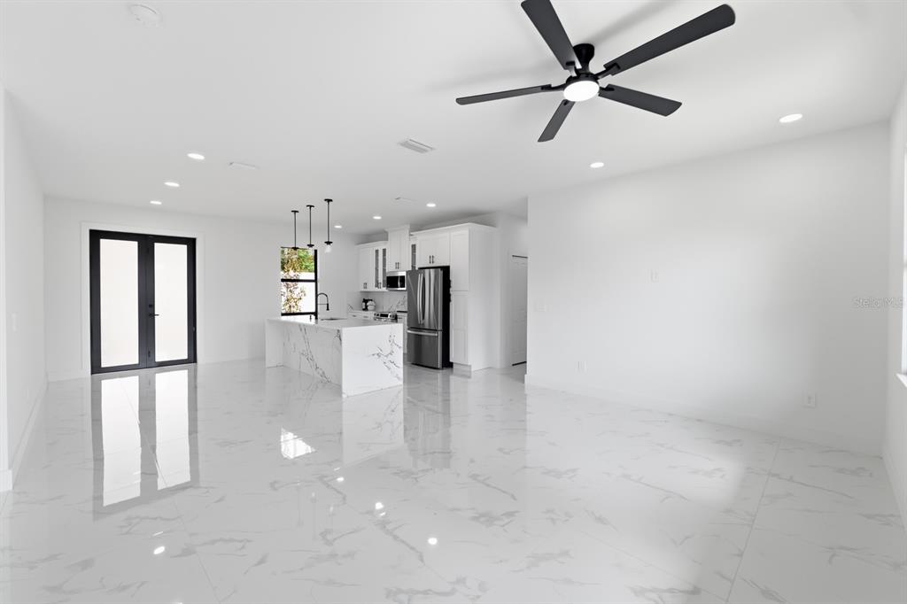 A modern open-concept kitchen and living area featuring white marble floors and a ceiling fan — 27426 AZEN LOOP, BROOKSVILLE, FL