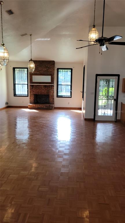 A living room features a brick fireplace, parquet wood flooring, and a vaulted ceiling — 1014 SE 10TH STREET, GAINESVILLE, FL