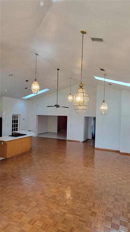 A spacious room with vaulted ceilings, parquet wood flooring, and several hanging pendant lights — 1014 SE 10TH STREET, GAINESVILLE, FL