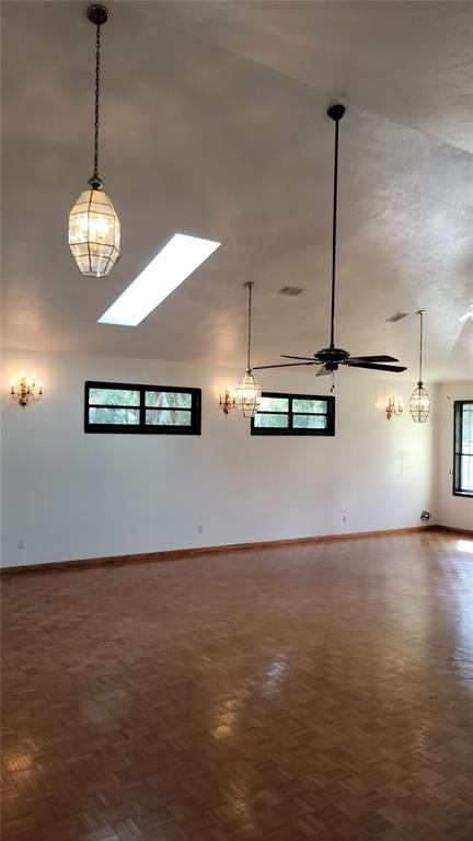 A spacious room with parquet wood floors, a vaulted ceiling, skylights, and multiple hanging light fixtures — 1014 SE 10TH STREET, GAINESVILLE, FL