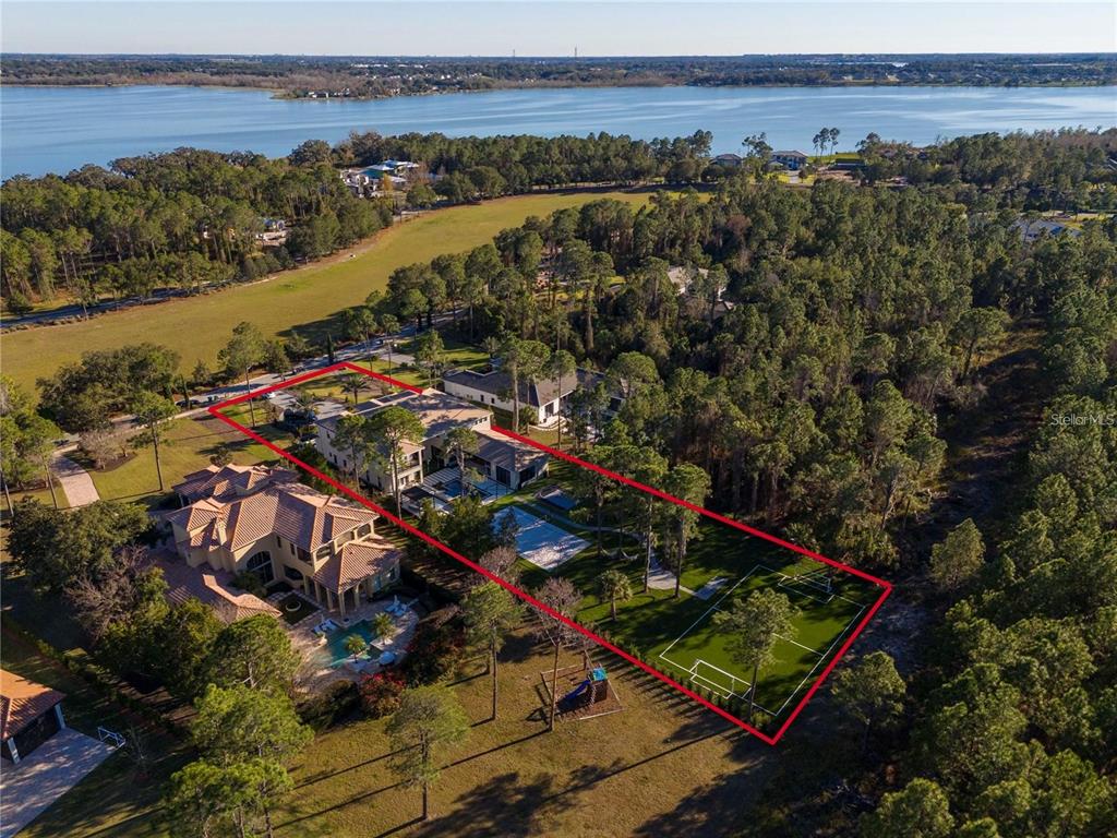 An aerial view shows a large house with a pool and a soccer field — 15926 PENDIO DRIVE, BELLA COLLINA, FL