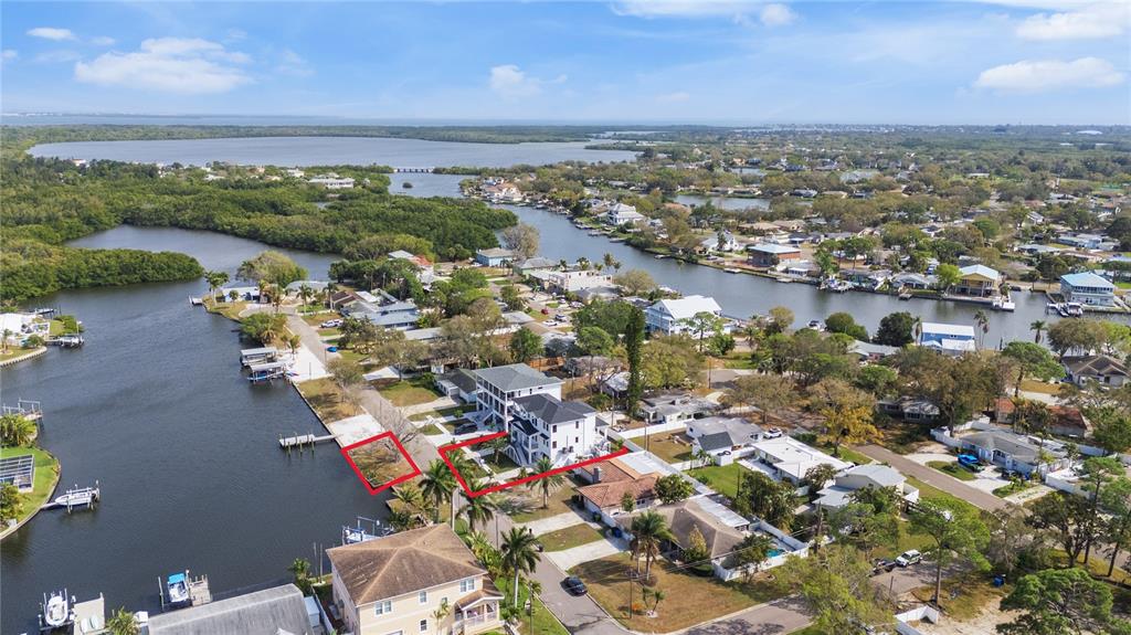 An aerial view shows a white multi-story house with a black roof near water — 220 90TH AVENUE NE, ST PETERSBURG, FL