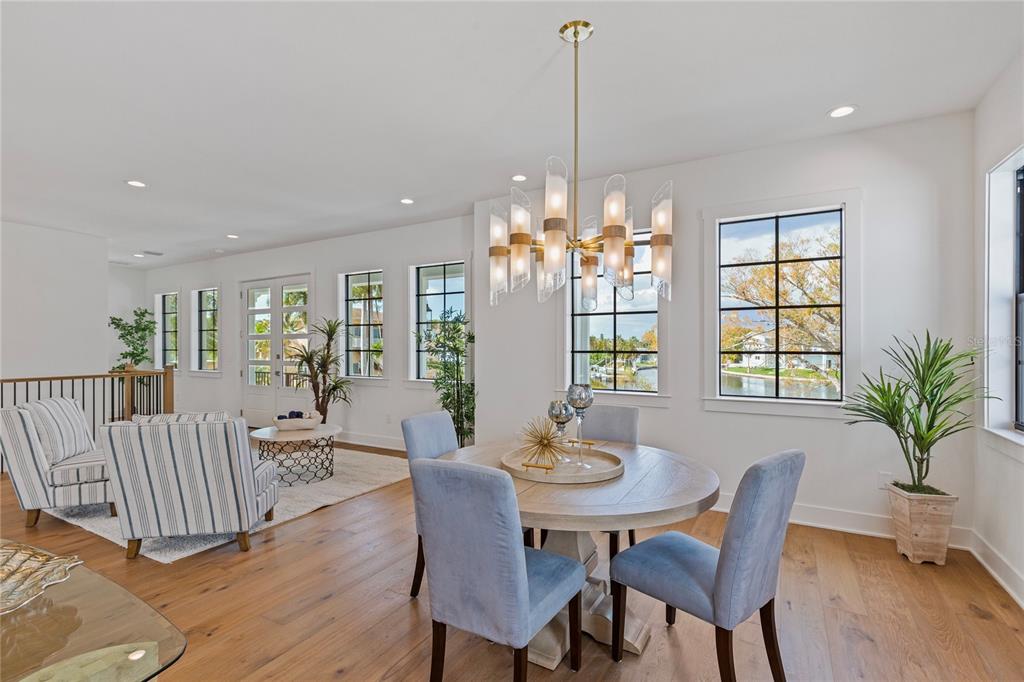 A white, elevated two-story house with a black roof, front staircase, and ground-level garage — 220 90TH AVENUE NE, ST PETERSBURG, FL