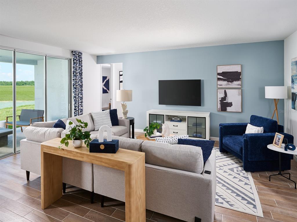 A living room features a light blue accent wall, gray sofa, and a navy armchair — 14152 HARVEST PINES LANE, HUDSON, FL