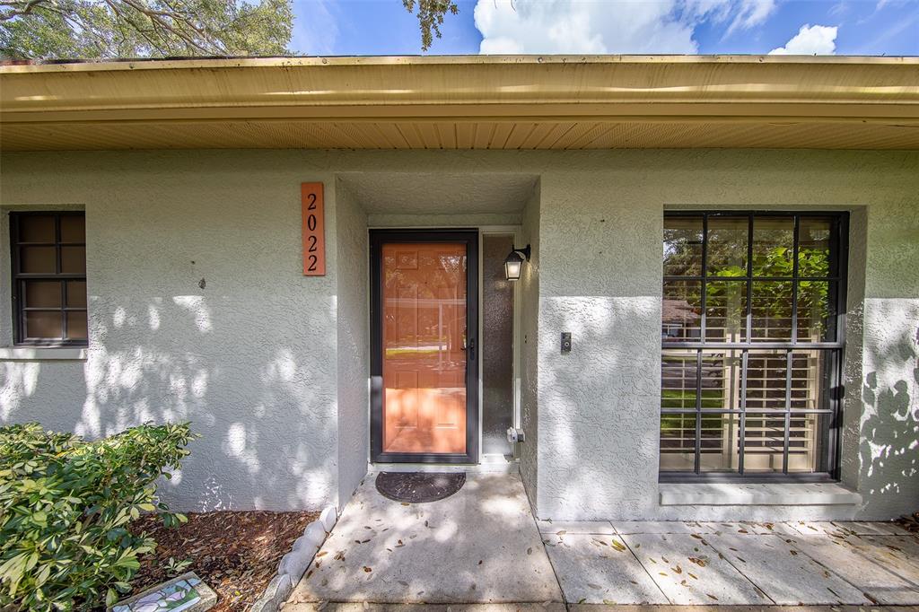 The exterior of a house features a light-colored stucco wall, a front door, and windows — 2022 NASH DRIVE, CLEARWATER, FL
