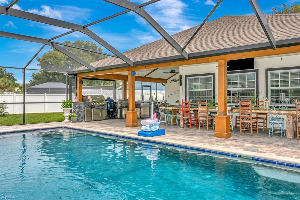 A covered patio features an outdoor kitchen, dining area, and a swimming pool with enclosure — 12007 VERMILLION WAY, RIVERVIEW, FL
