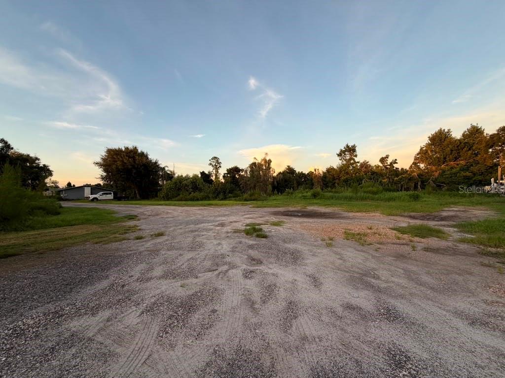 A wide, unpaved dirt lot with sparse grass and trees under a clear sky — 6012 LAND O LAKES BOULEVARD, LAND O LAKES, FL
