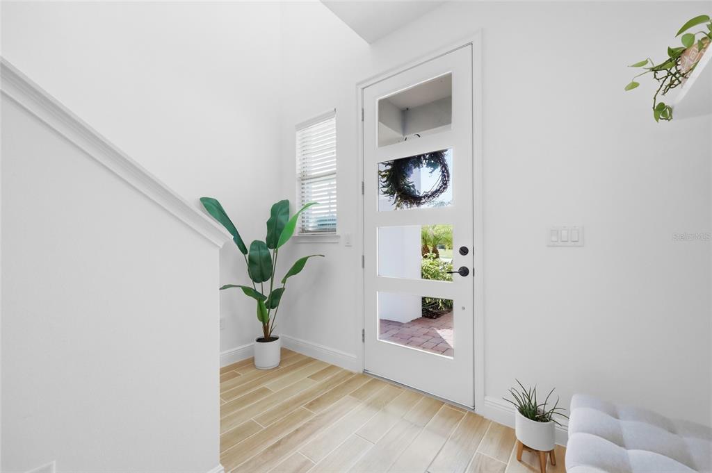 A bright entryway features white walls, light wood-look tile flooring, and a modern glass-paneled door — 6699 ALDER ROAD, ST CLOUD, FL