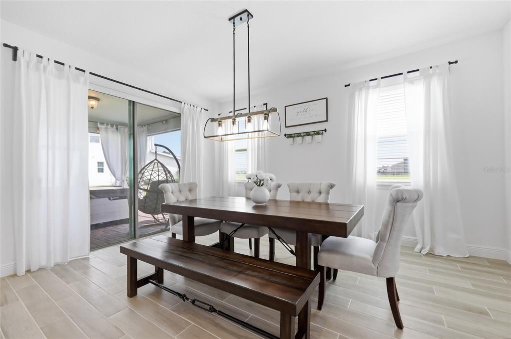 A dining room features a wooden table, a bench, upholstered chairs, and a sliding glass door — 6699 ALDER ROAD, ST CLOUD, FL