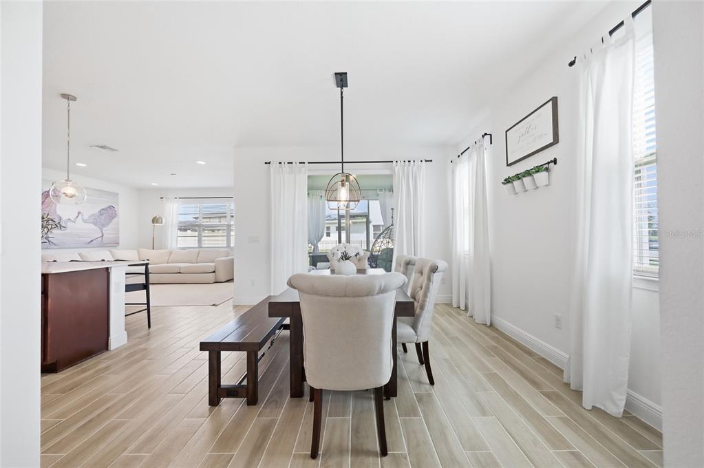 A dining area with a wooden table, upholstered chairs, and a bench on tile flooring — 6699 ALDER ROAD, ST CLOUD, FL