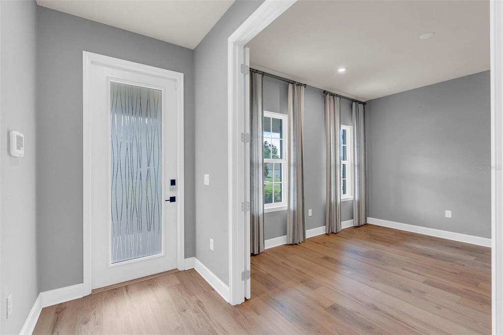 An entryway features light gray walls, wood-look flooring, two white doors, and a wooden console table — 3009 ROBLES ROAD, CLERMONT, FL