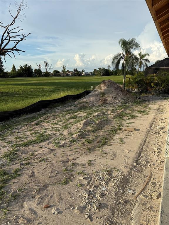 A dirt backyard with a pile of sand, a black silt fence, and a golf course — 18 CADDY ROAD, ROTONDA WEST, FL