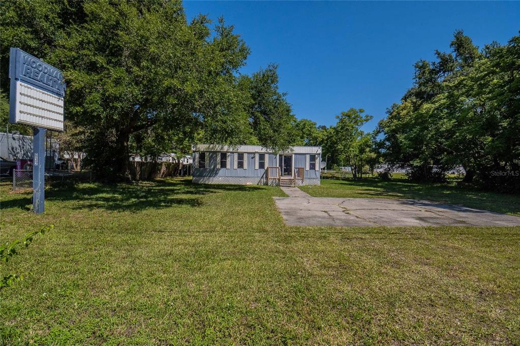 A single-story manufactured home sits on a grassy lot with a concrete driveway and sign — 632 COMMONWEALTH AVENUE SW, POLK CITY, FL