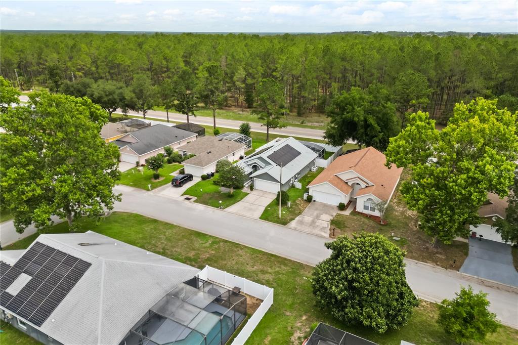 An aerial view shows several suburban houses with driveways, swimming pools, and surrounding trees — 638 PINE CONE DRIVE, DAVENPORT, FL