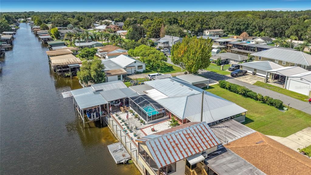 An aerial view shows a waterfront house with a screened pool, boat dock, and canal — 116 BREAM STREET, HAINES CITY, FL