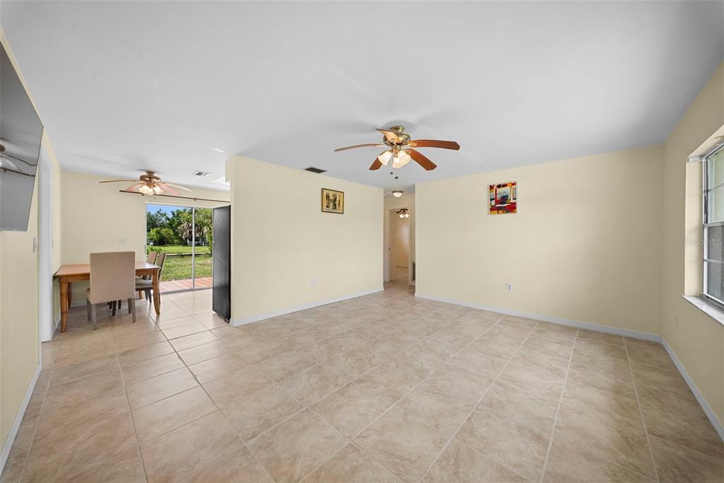 A spacious, tiled living area features a ceiling fan, light yellow walls, and a dining space — 154 DANFORTH DRIVE, PUNTA GORDA, FL