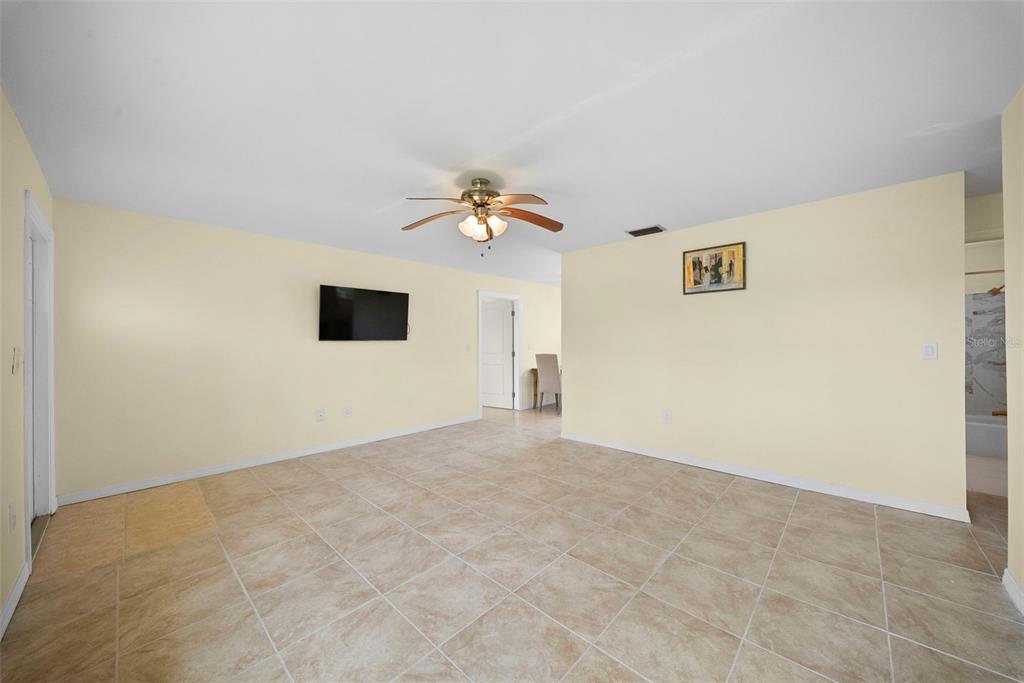 A spacious room features light yellow walls, beige tile flooring, and a ceiling fan — 154 DANFORTH DRIVE, PUNTA GORDA, FL