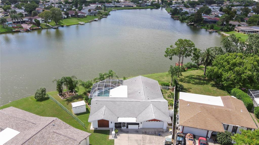 An aerial view shows a waterfront house with a screened pool and a large lake — 9619 TOWANDA LANE, PORT RICHEY, FL