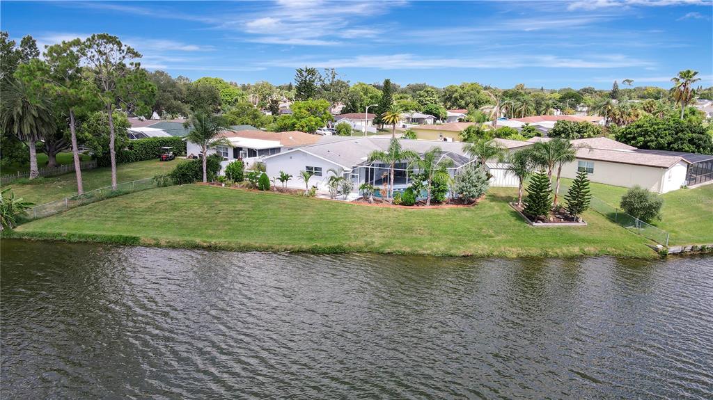 An aerial view of a waterfront house with a screened pool and a large lawn — 9619 TOWANDA LANE, PORT RICHEY, FL
