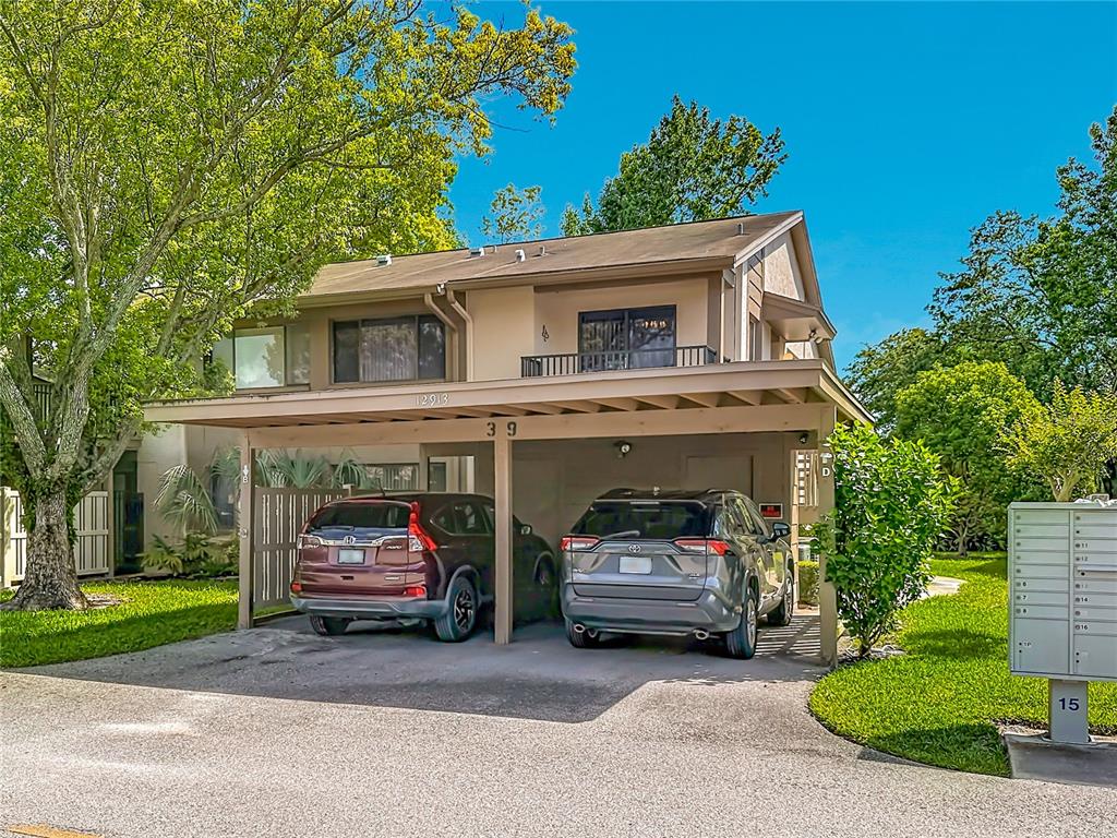 A two-story residential building features a ground-level carport with two parked vehicles — 12913 FAIRWAY DRIVE UNIT D, HUDSON, FL